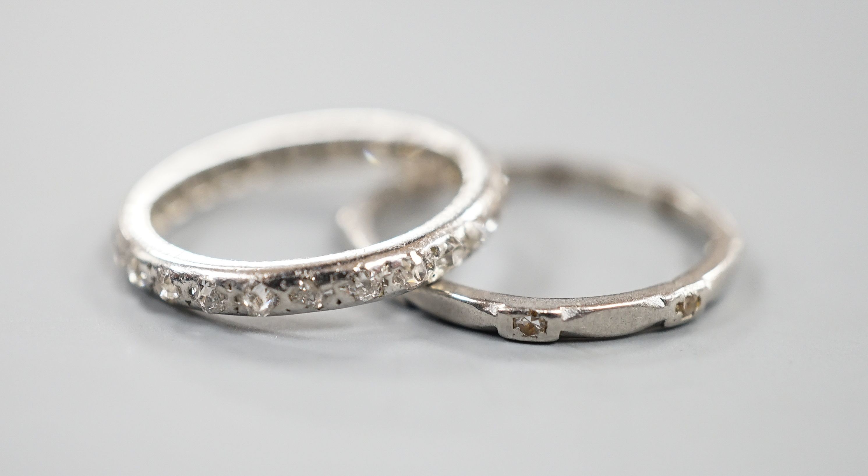 A white metal and diamond chip set full eternity ring, size J and a white metal (stamped Pt) and diamond set eternity ring (two stones missing), size L, gross weight 4.2 grams.